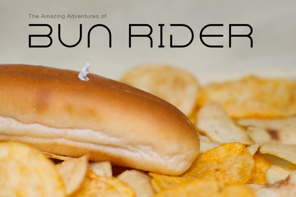 The Amazing Adventures of Bun Rider - an image of a plastic figure riding a bread roll in sand dunes made from potato chips